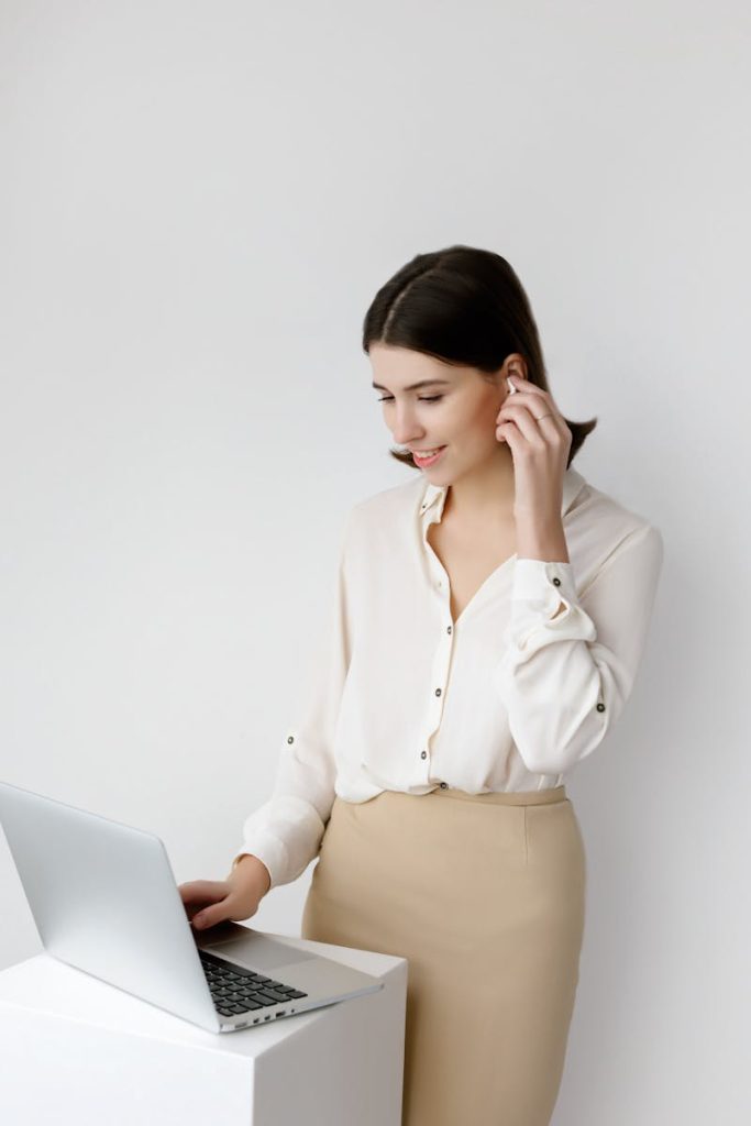 Confident businesswoman in elegant attire working on a laptop indoors, showcasing a modern professional setting.