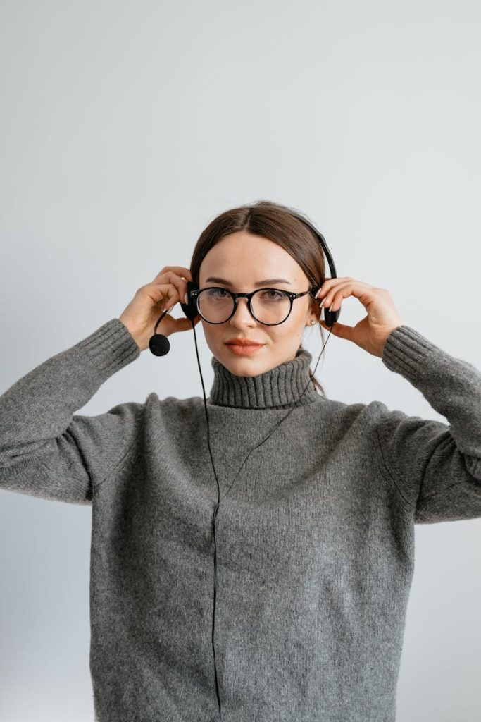 Caucasian woman in gray sweater with headset offering customer service assistance.